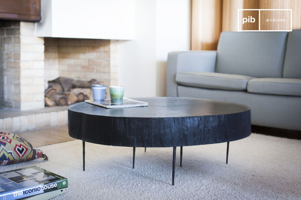 Gruesa mesa de madera negra con finas patas metálicas.