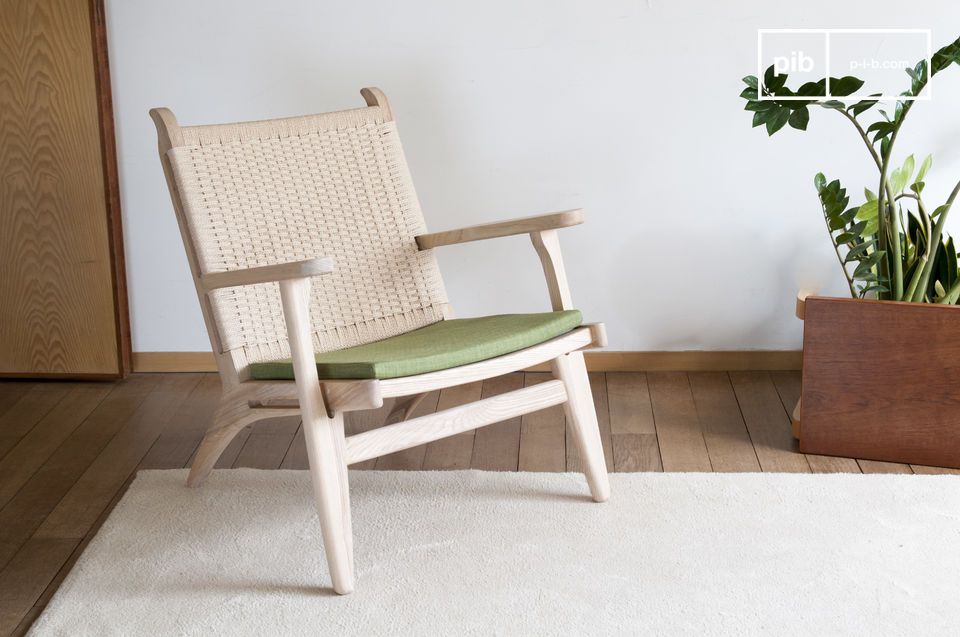 Un sillón natural que combina madera clara, ratán tejido y verde oliva.